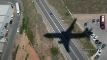 Shadow of a commercial airplane flying over a town.