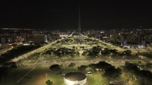 Drone flies toward a green TV Tower lit up at night in Brasilia, Brazil