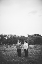 two women holding hands in a field
