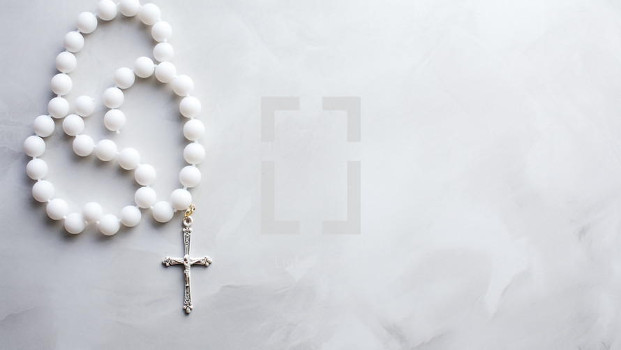 Crucifix rosary on white background with copy space