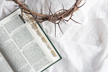 open Bible and crown of thorns on a white linen background 