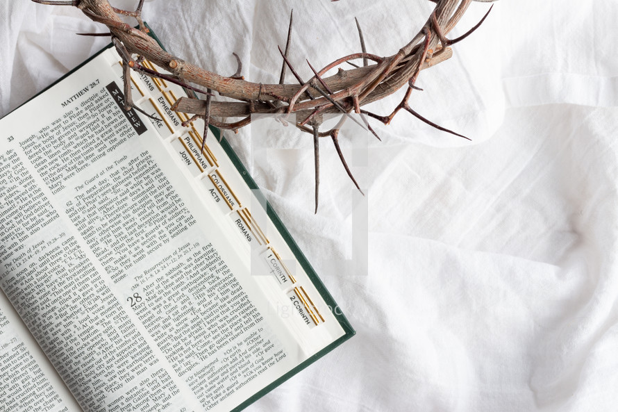 open Bible and crown of thorns on a white linen background 