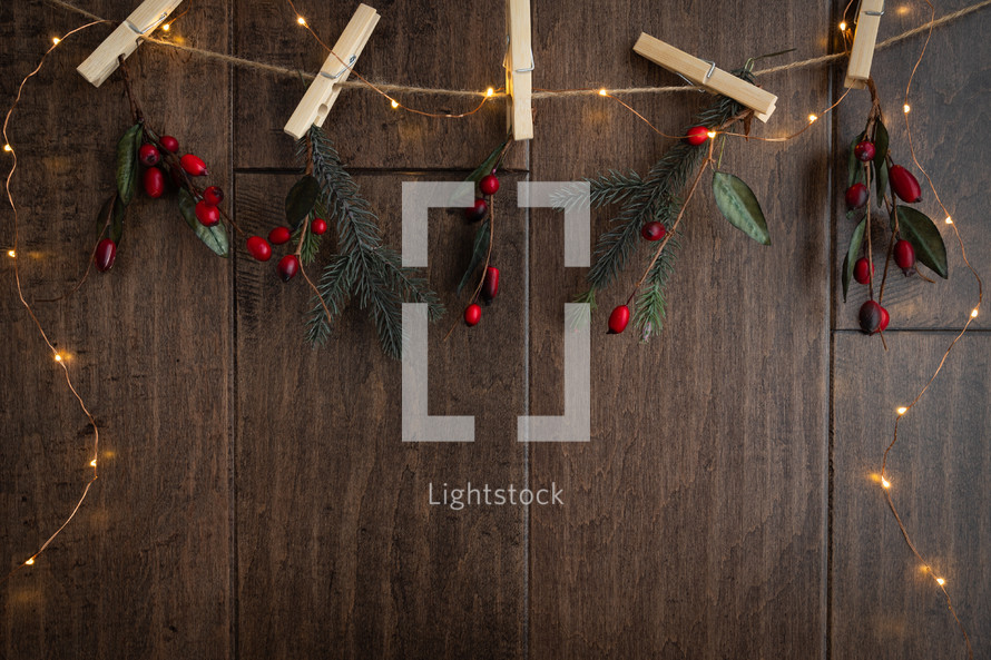 clothespins, red berries and fairy lights on a wood background 