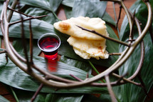 communion cup and torn bread on palm fronds and crown of thorns 