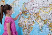 A young caucasian girl looking at Europe on a large map. - for editorial use only