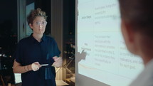 Young Woman Giving Business Presentation with Colleague at Night Meeting
