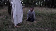 A young teen boy praying in nature encounters Jesus Christ in cinematic slow motion.