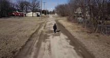 Aerial, drone shot of young man, teenager with backpack and winter coat walking in cinematic slow motion. A young, teen boy walking to high school or young homeless man. 