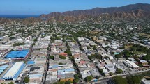 Aerial shot drone flies north of city toward mountains.