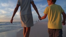 mother and son walking on a beach 