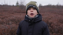 Young boy outdoors takes deep breath 