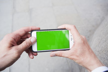 Personal perspective of a man using a smartphone with a green screen- for editorial use only 