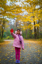 a little girl holding a red fall leaf 