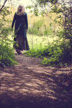 A woman walking along a path through the woods.