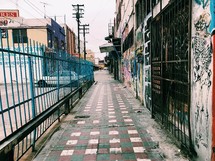 fence, gates, and graffiti on a city sidewalk 