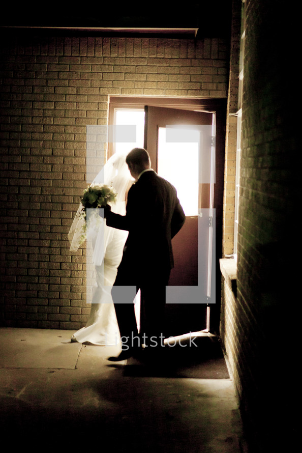 Groom holding the door open for his bride