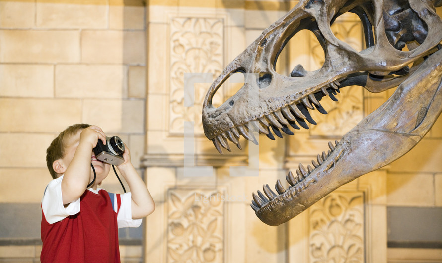 Caucasian boy photographing a dinosaur on an old camera