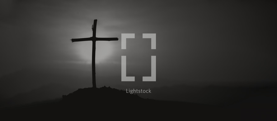 Cross on a hill during a vibrant sunrise - black and white