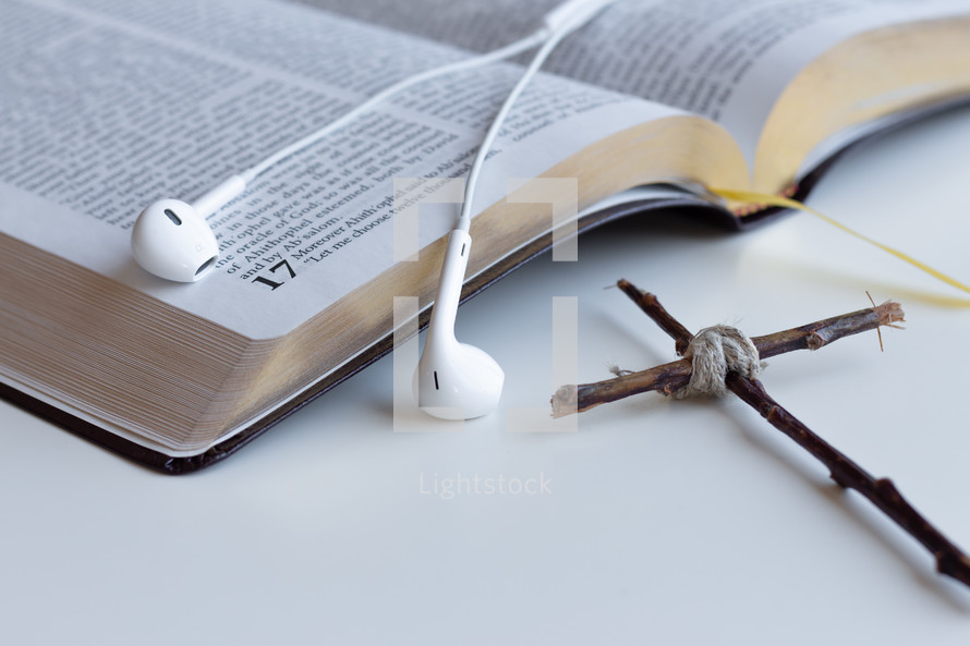 cross made of sticks and earbuds on the pages of a Bible 