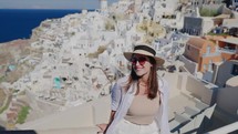 Tourist travel woman in Oia, Santorini, Greece. Happy young woman enjoying view. Beautiful girl visiting the Greek island.

