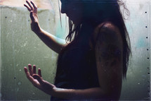 Conceptual, grungy portrait of a woman standing in light.