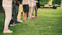 row of people standing outdoors in grass 