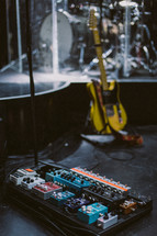 guitar pedals, guitars, and drums on stage 