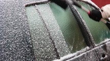 Brushing And Scraping Snow Off Frozen Car Windows. close up, lateral shot