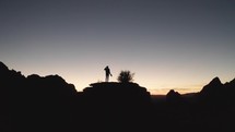 Silhouette of a man on a hill, contemplating life as he looks out of a vast Arizona desert sunset.