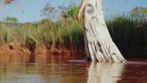 Girl feet and legs walking on water slow motion. Wearing dress
