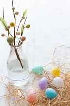 vase and pastel Easter eggs in straw 