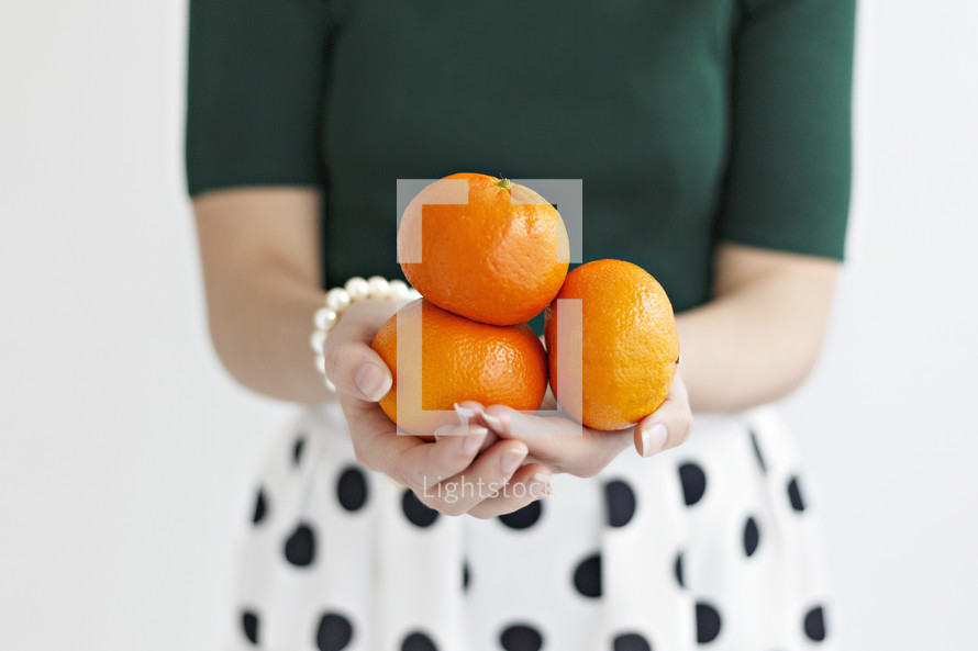 a woman holding oranges 