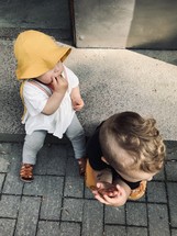 siblings sitting on a curb 