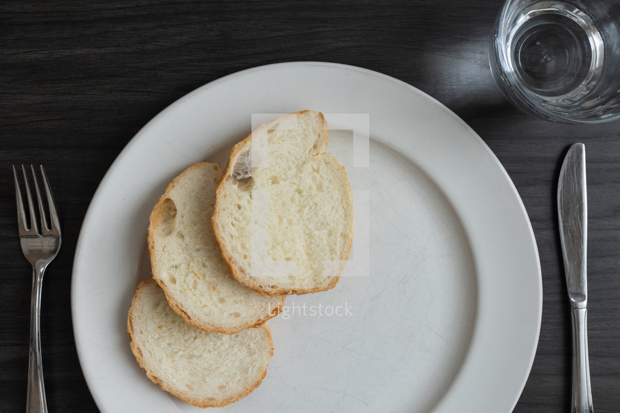 Bread and water meal on a dark wood table