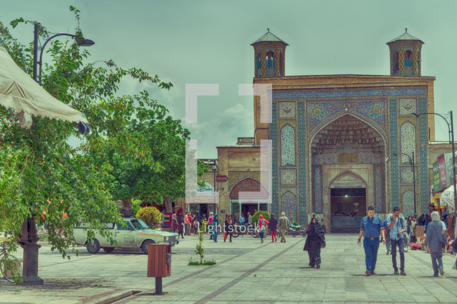 people walking through a courtyard in front of a mosque 