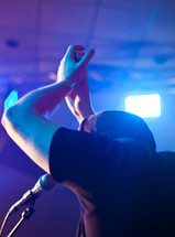 man clapping his hands and singing on stage at a concert 