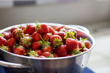 backlit colander full of strawberries