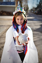 a child in a live nativity scene holding a piggy bank 