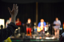 man with raised arms listening to music at a worship service 