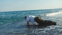 Soldier does push ups in the sea waves