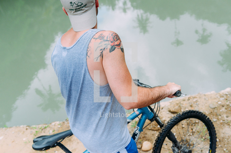 A bicycle rider next to a lake.