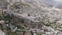 Drone view of Gjirokastra Castle on hilltop overlooking historic UNESCO World Heritage City of Gjirokastër, Albania
