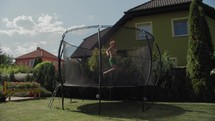 A twelve-year-old boy enjoys jumping on a trampoline in a home garden