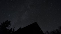 Night galaxy milky way above a wooden hut in the forest