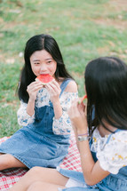 girls eating watermelon on a picnic blanket 