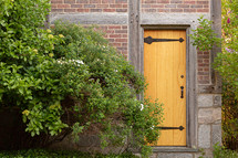 old door in brick house surrounded by green bushes