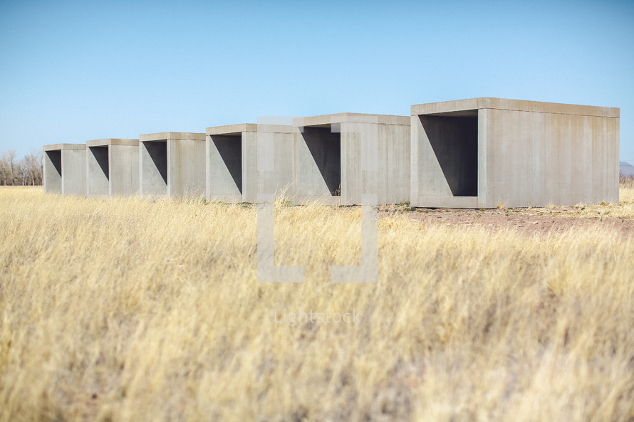 Row of cement storage containers in a field.
