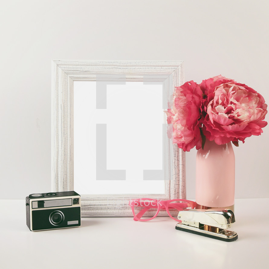 camera, stapler, glasses, flowers in a vase, and mirror 