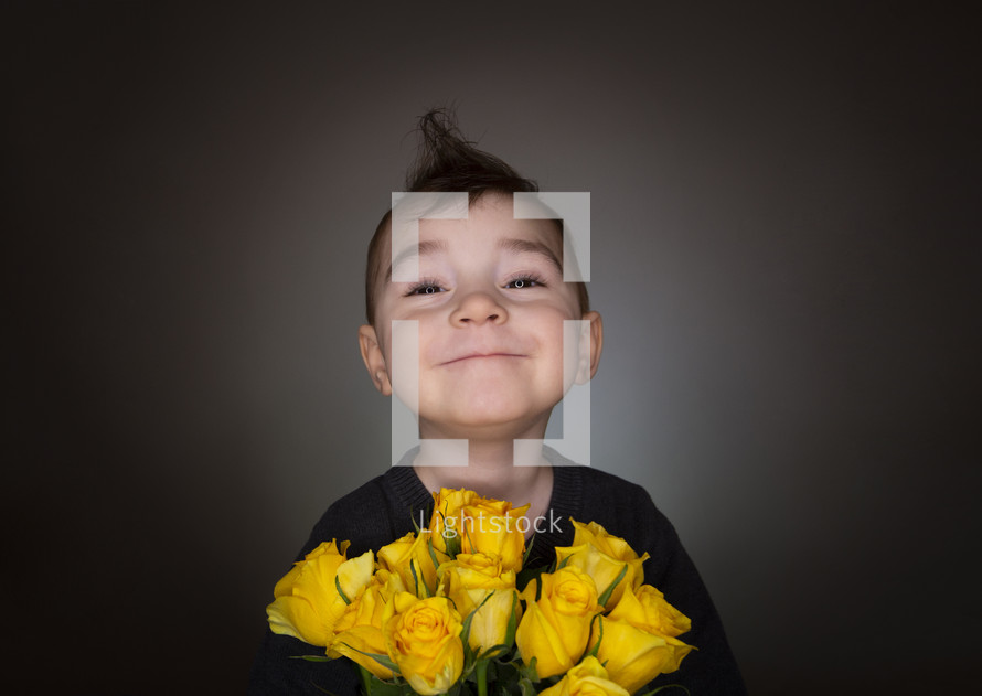 smiling boy holding a bouquet of yellow roses 