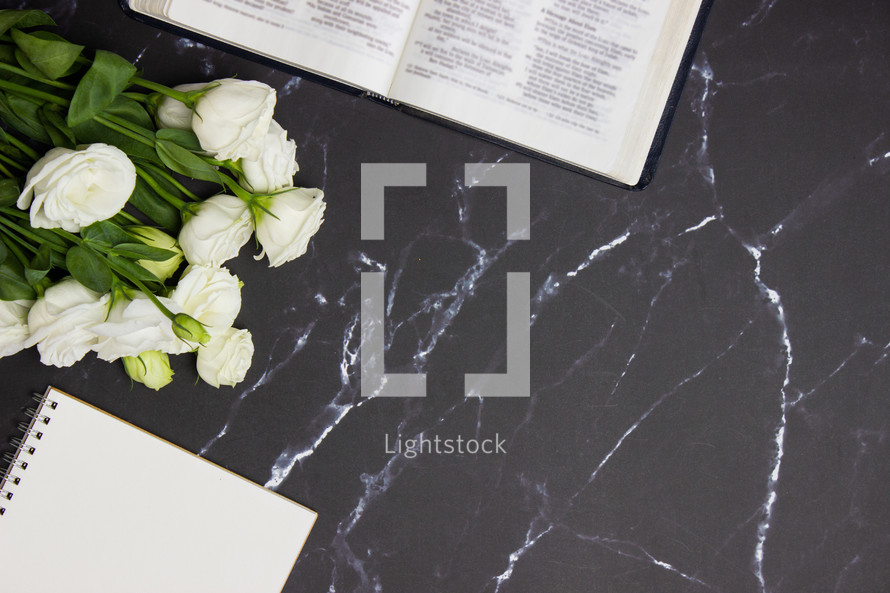 open Bible and notebook on a black marble background 